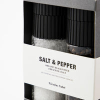 Close-up of French sea salt and black peppercorn grinders inside the Nicolas Vahé gift box, with matte black ceramic caps