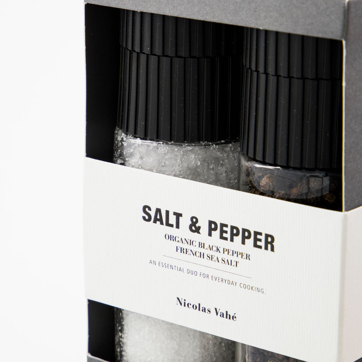 Close-up of French sea salt and black peppercorn grinders inside the Nicolas Vahé gift box, with matte black ceramic caps