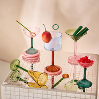 assortment of colourful cocktail glasses including pink coupe glass on tiled surface