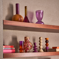 Colour-block Farve vase displayed among glass and ceramic vases in warm tones.