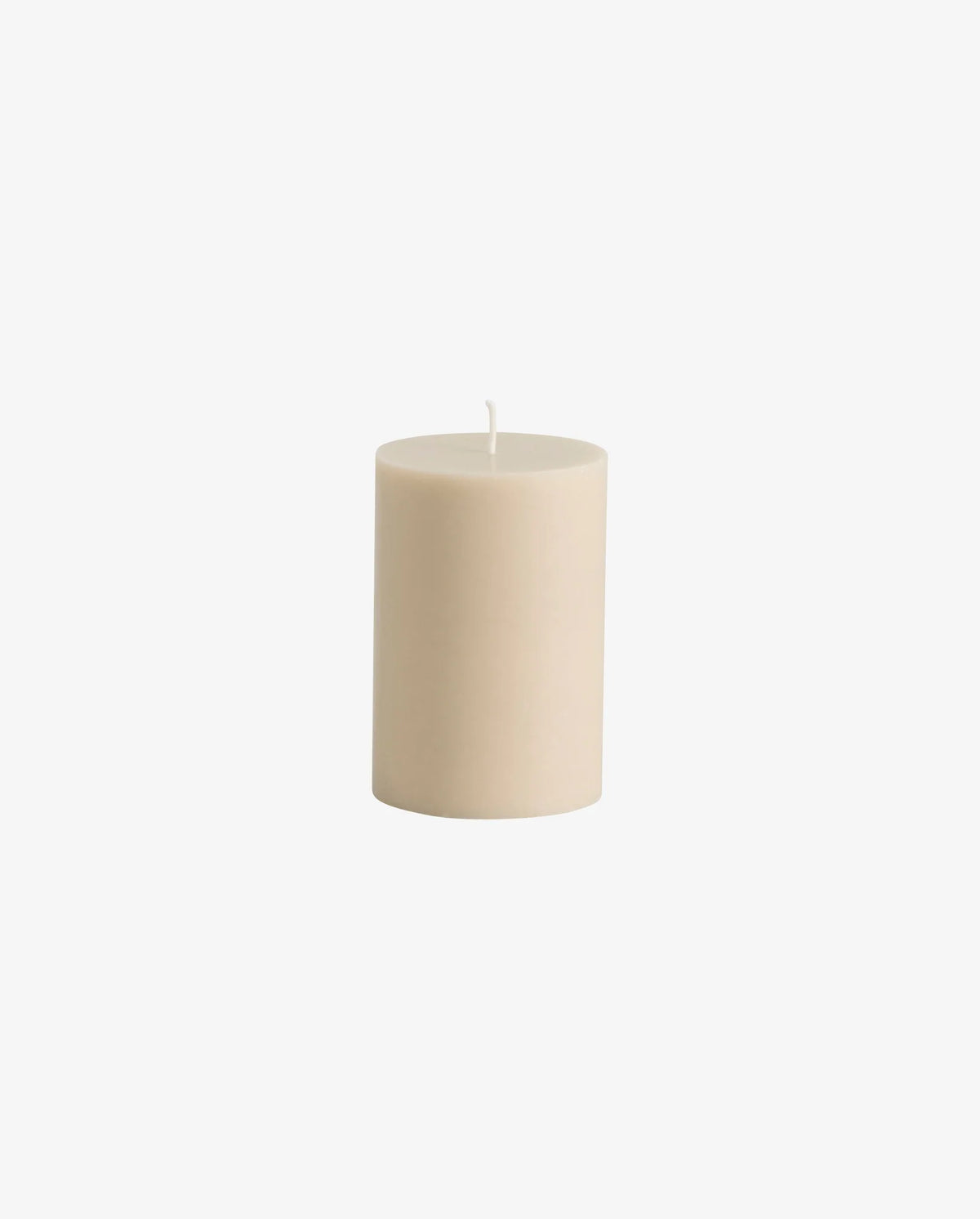 Beige pillar candle by Nordal displayed on a mantelpiece with other Nordal candles