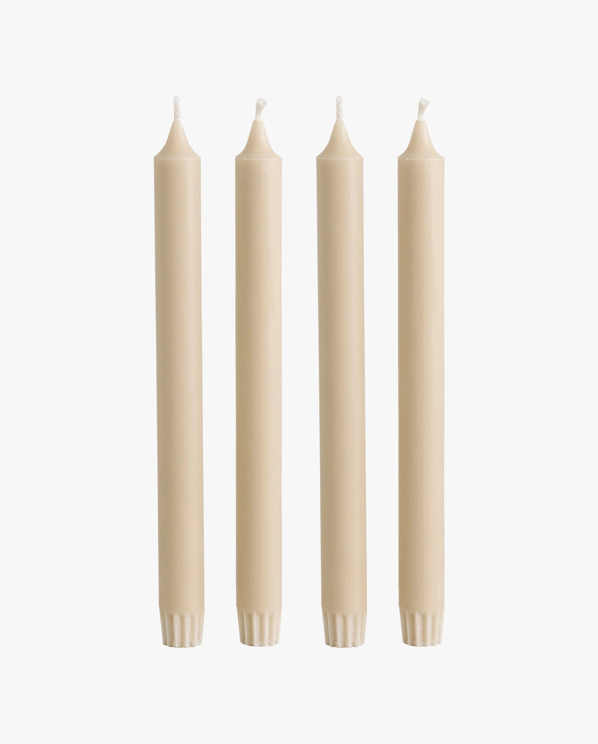 row of lit candles on a white mantelpiece shelf: two ceramic fish-shaped candlesticks holding cream taper candles, a cluster of cream and dark olive green pillar candles of varying heights, and a brass candlestick holding another taper candle, with framed artwork on the wall behind