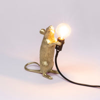 Seletti Gold standing Mouse Lamp switched on, with a warm glowing bulb