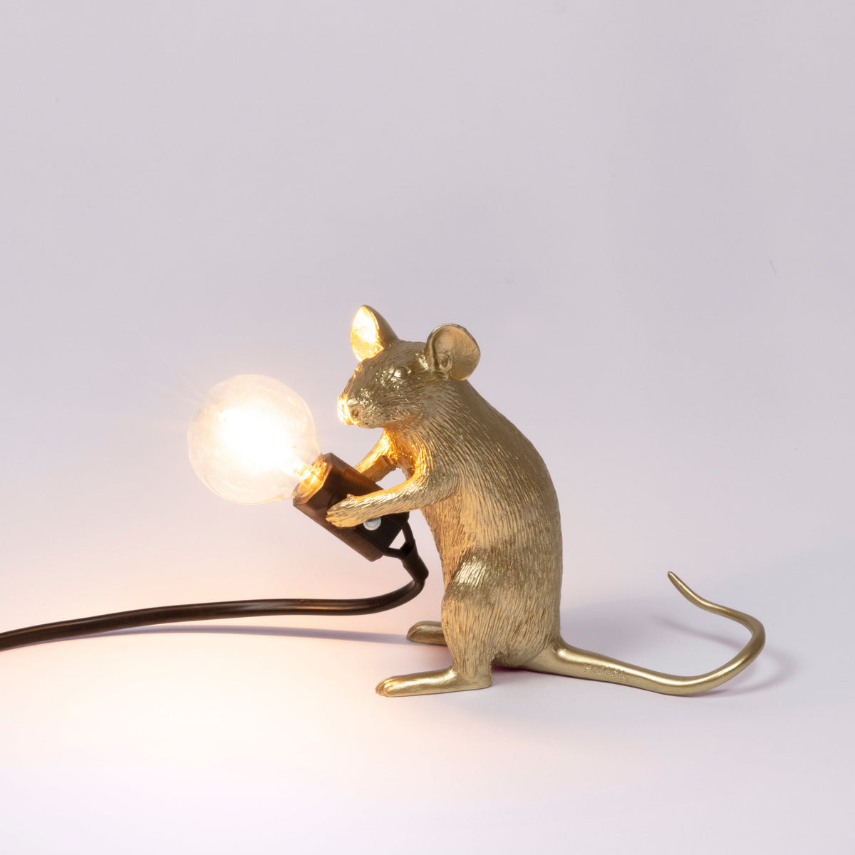 Seletti Gold sitting Mouse Lamp switched on, with a warm glowing bulb