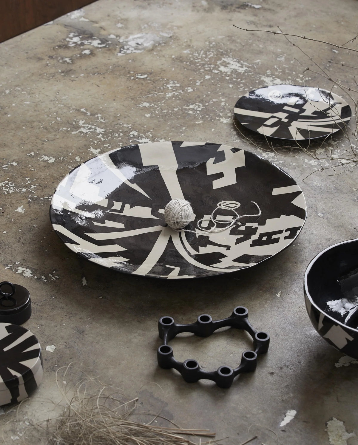 LIPSI decorative plate by Nordal in black and beige, angled view showing the graphic art deco pattern and shallow profile