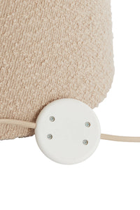 Close-up of a beige textured lampshade with a white base on a white background