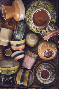 Overhead view of HKLIVING 70s Ceramics cups, bowls and plates in mixed reactive glazes on a dark surface