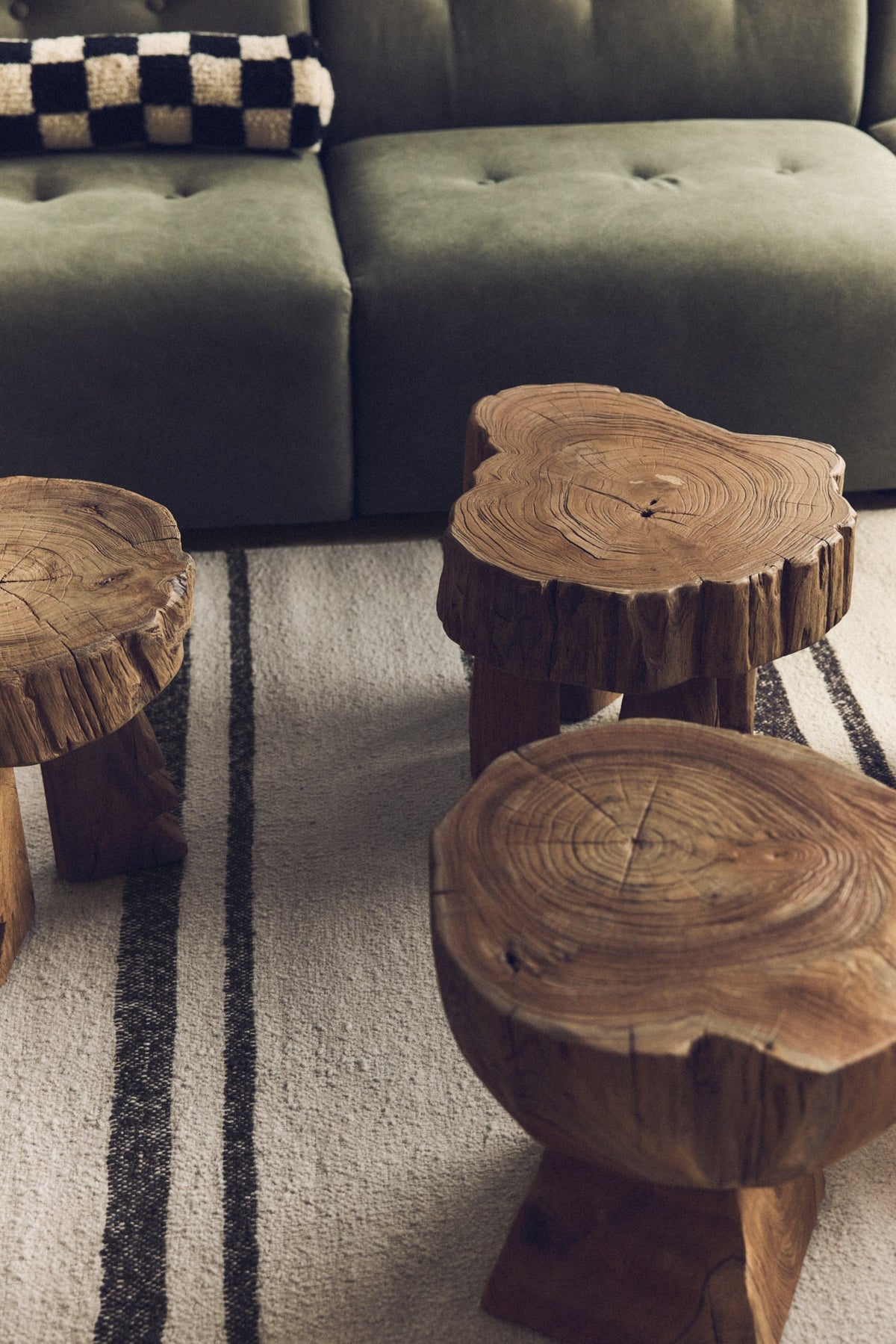 HKLIVING log wooden stools in solid teak grouped on a striped rug in front of a green sofa