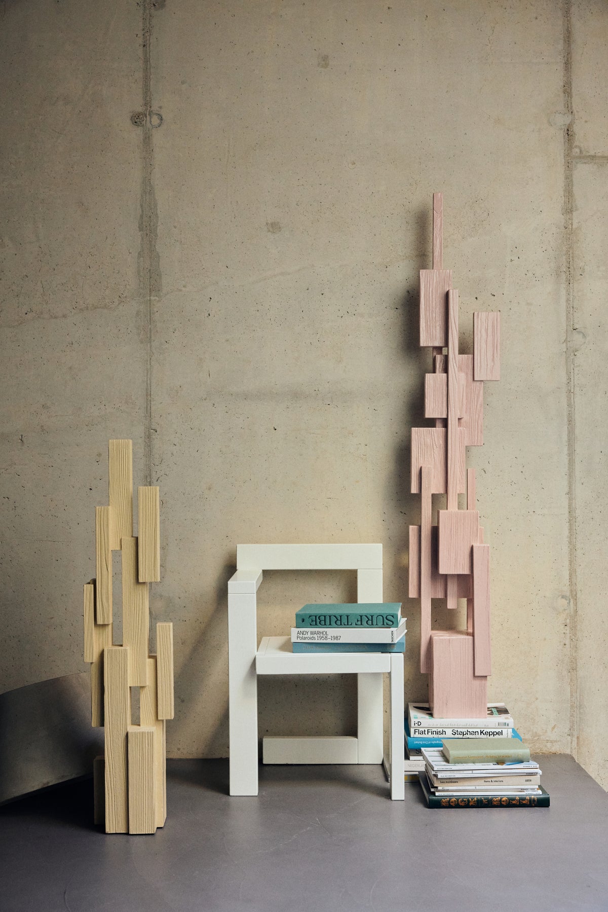 HKLIVING soft pink and cream Skyscraper sculptures styled together with a white chair and books against a concrete wall
