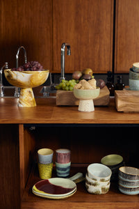 HKLIVING Marbled Bowl on Base in Ochre filled with grapes on a kitchen counter, styled with fresh fruit and ginger
