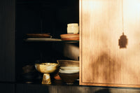 HKLIVING Marbled Bowl on Base in Ochre displayed on an open cabinet shelf among other ceramics and plates