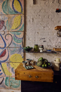 70s Ceramics tapas bowl on base in Brew styled on a kitchen counter beside a colourful painted tile backdrop