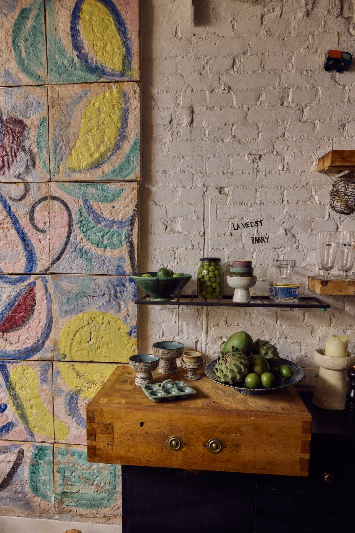 70s Ceramics tapas bowl on base in Brew styled on a kitchen counter beside a colourful painted tile backdrop