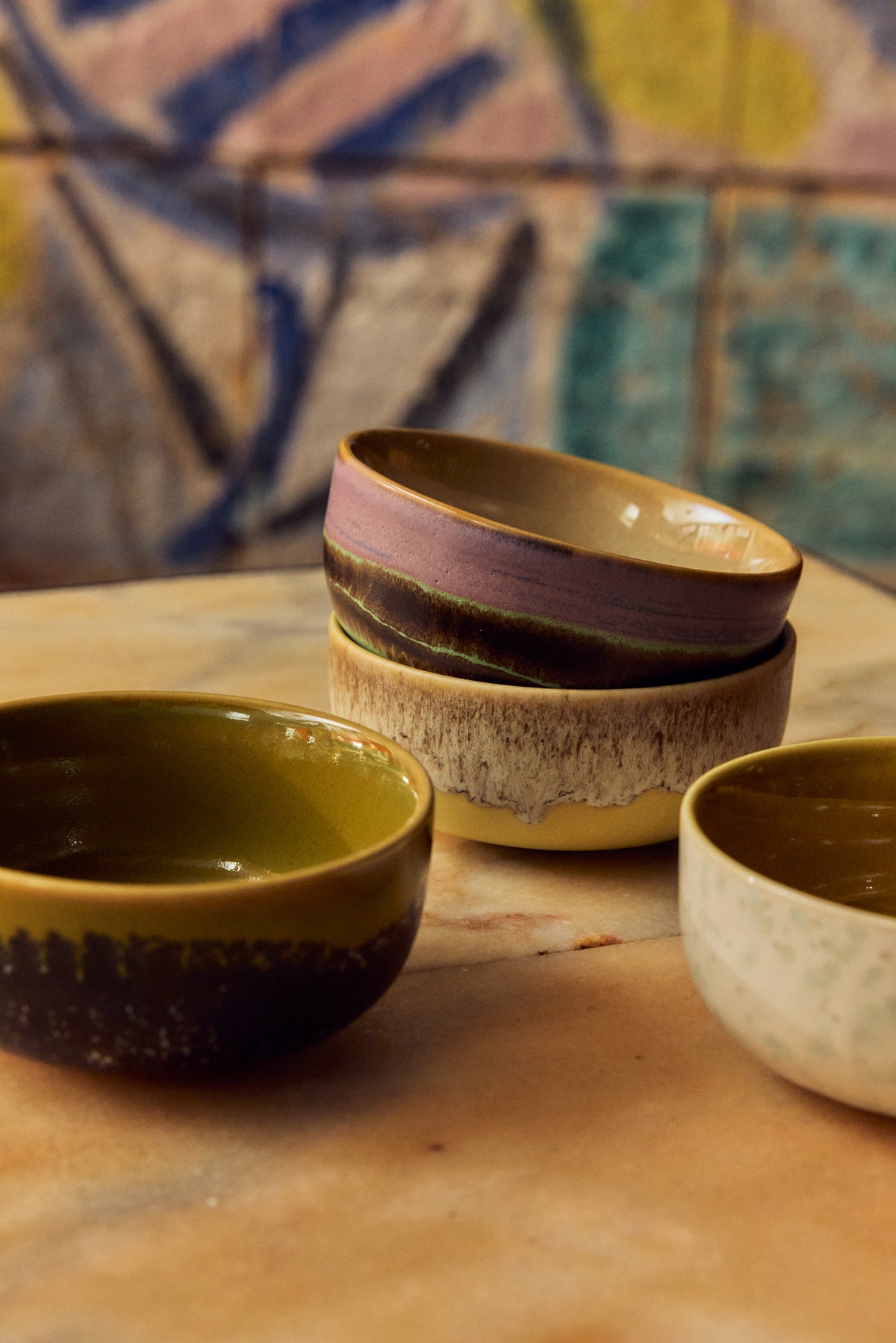 Stack of four 70s ceramics tapas bowls in Sweet on a marble table, styled with an artistic painted tile background