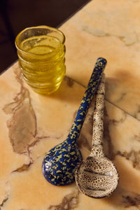 70s Ceramics serving spoons in Blues by HKLIVING styled on a marble table beside an amber glass tumbler