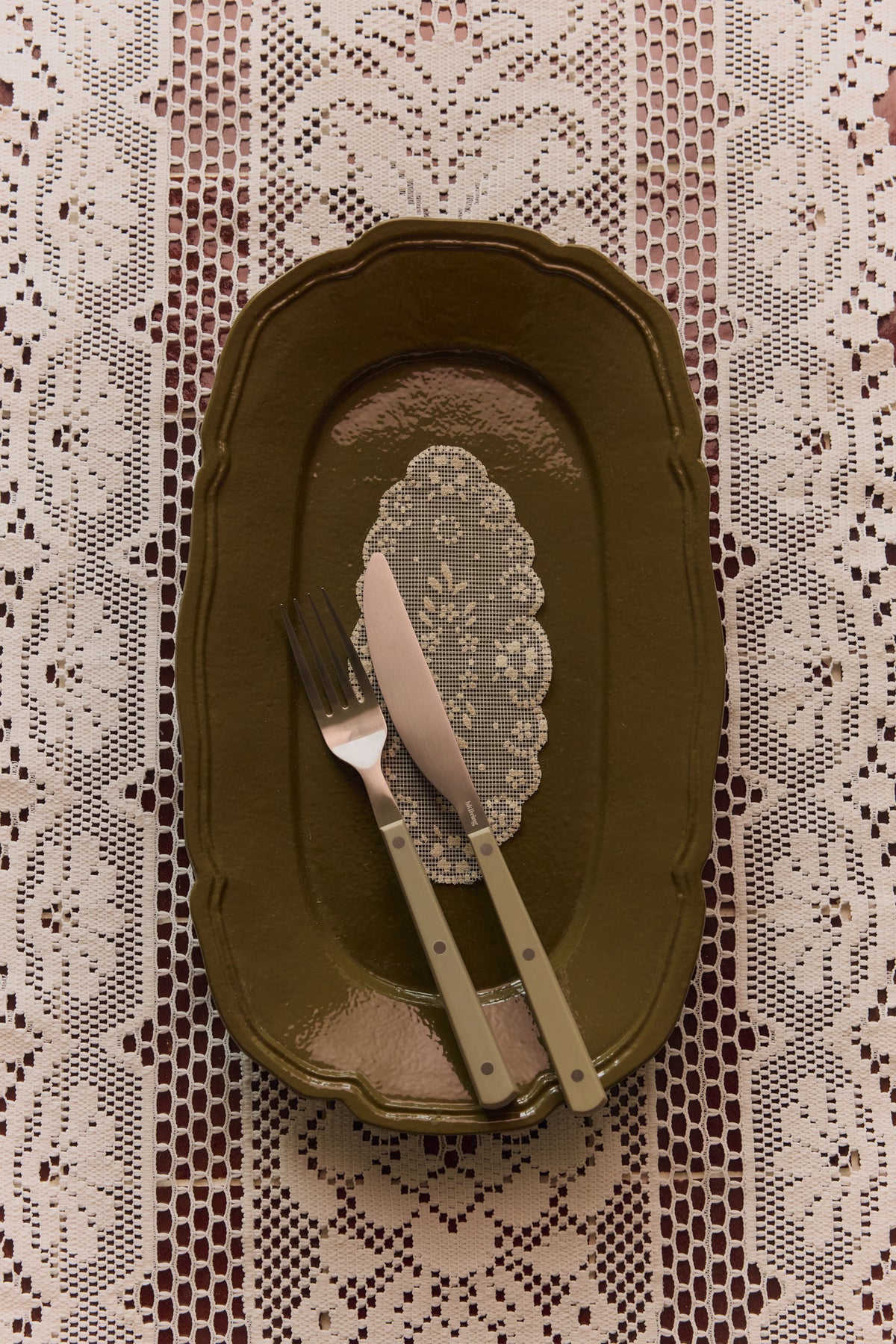 HKLIVING olive knife and fork resting on an olive scalloped plate over a lace tablecloth