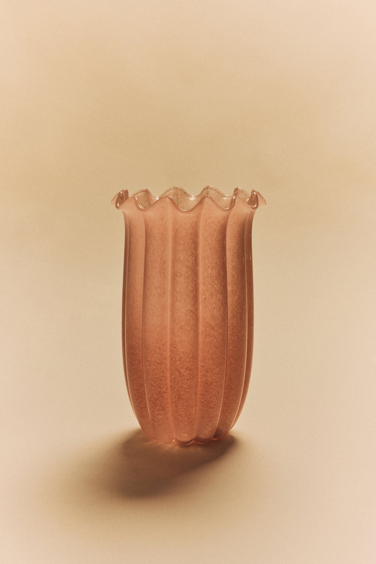 Ribbed glass vase in peach by HKLIVING styled on a warm beige background