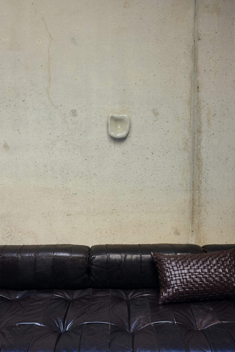 HKLIVING Dent Wall Sculpture in Overcast mounted on a concrete wall above a dark leather sofa