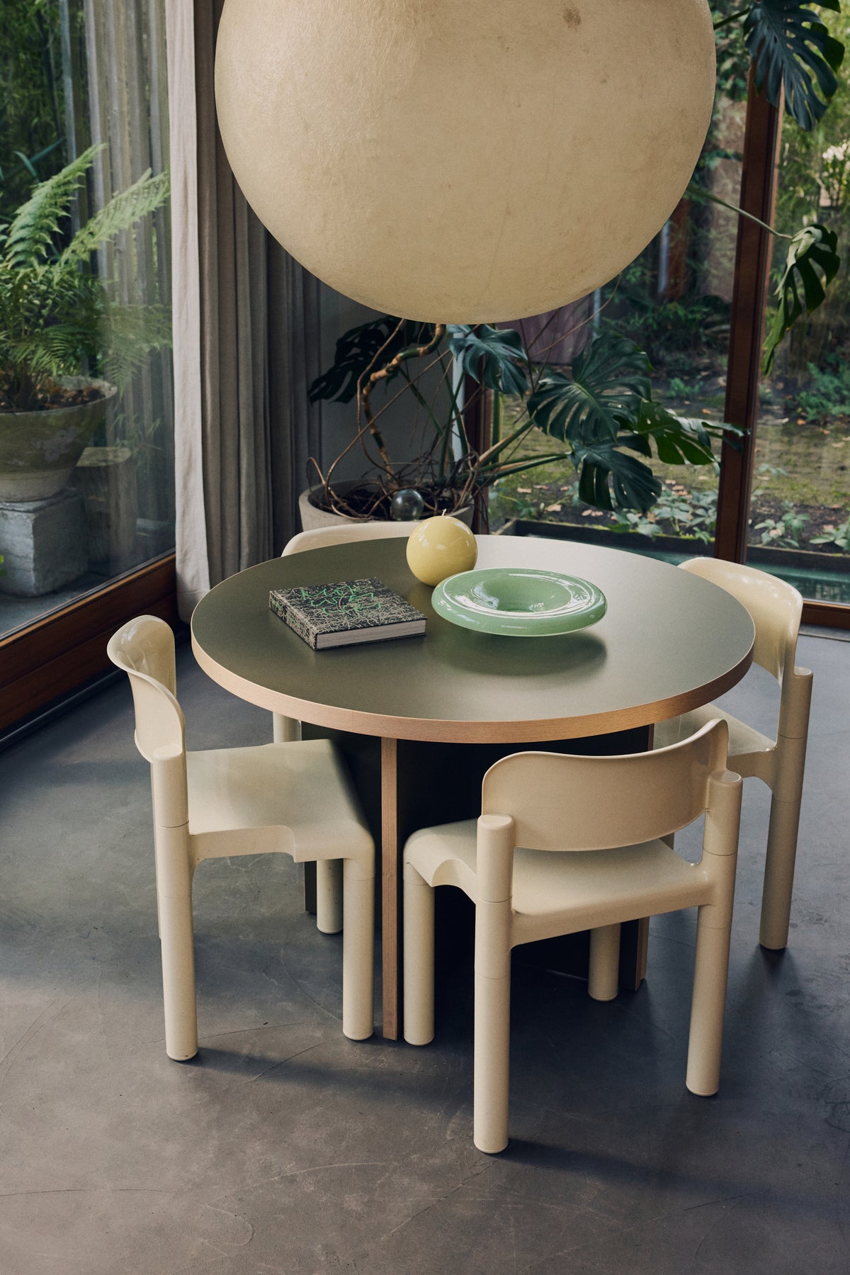Olive HKLIVING 110cm round dining table with cream dining chairs under a large paper globe pendant by a garden window