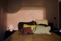 Chestnut brown ruffle cushion styled on a bed among mixed colour cushions