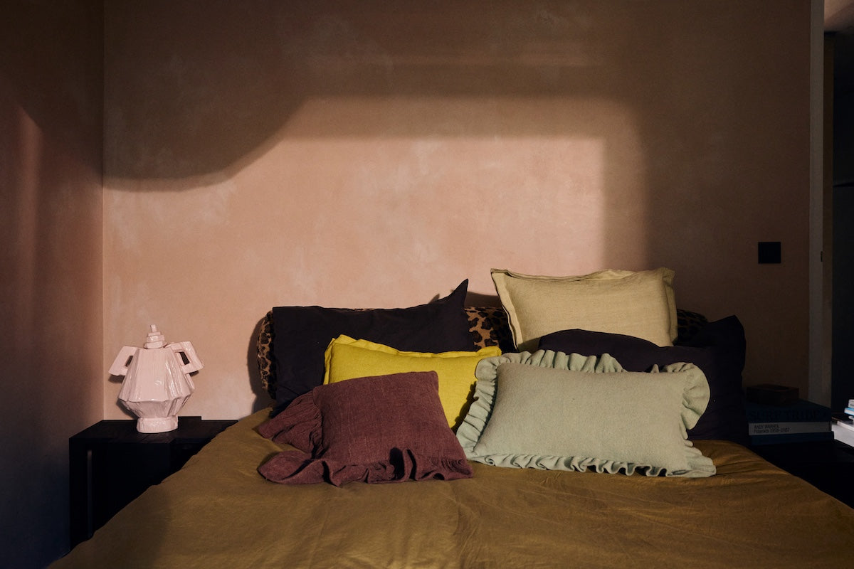 Chestnut brown ruffle cushion styled on a bed among mixed colour cushions