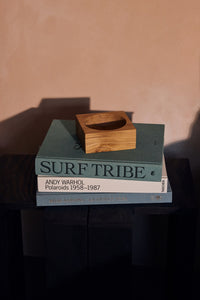 Small HKLIVING teak cube bowl displayed on a stack of coffee table books against a pink wall