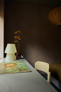 HKLIVING Glassfibre Table Lamp in Off White styled on a concrete shelf alongside dried flowers and a chair