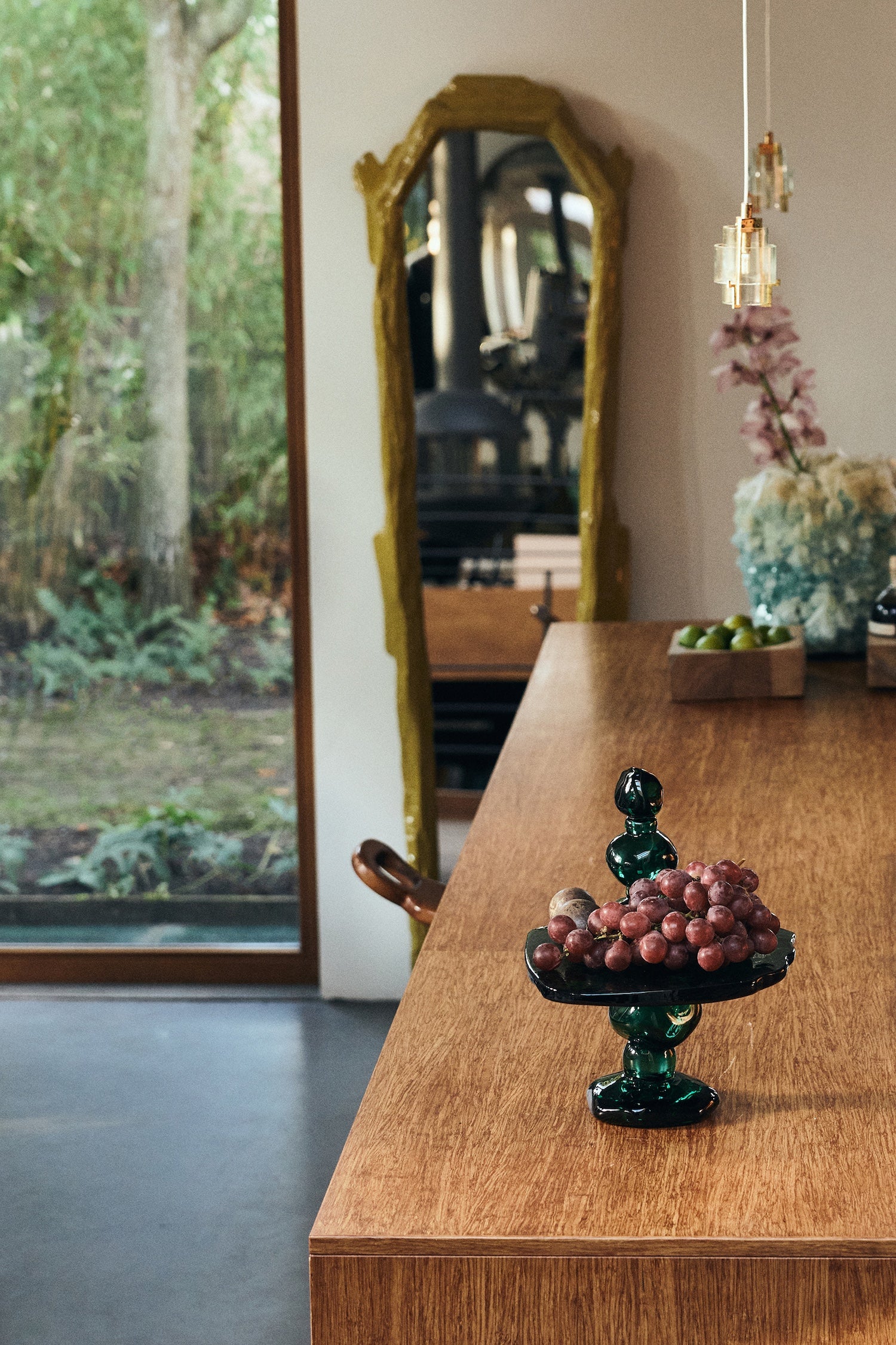 Emerald glass dessert stand styled with grapes on a wooden sideboard