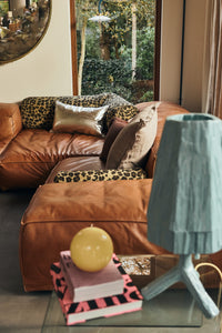 Silver faux leather cushion styled on a tan leather sofa with patterned cushions