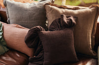 Dusty peach linen cushion layered with grey and brown linen cushions
