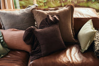 Chestnut brown hkliving ruffle cushion styled among linen cushions on a leather sofa