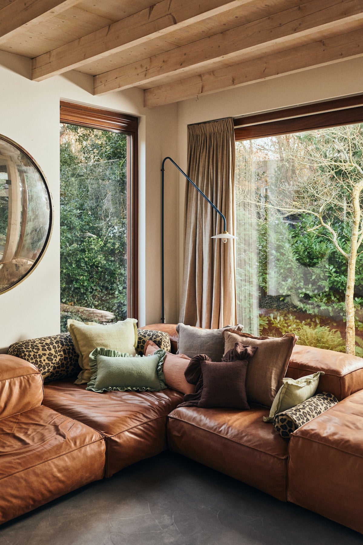 Leather sectional sofa styled with leopard print bolster cushions and an assortment of linen scatter cushions