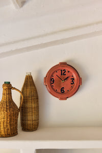 Terracotta Wall Clock by HKLIVING hanging on a plain wall beside woven wicker-covered bottle vases