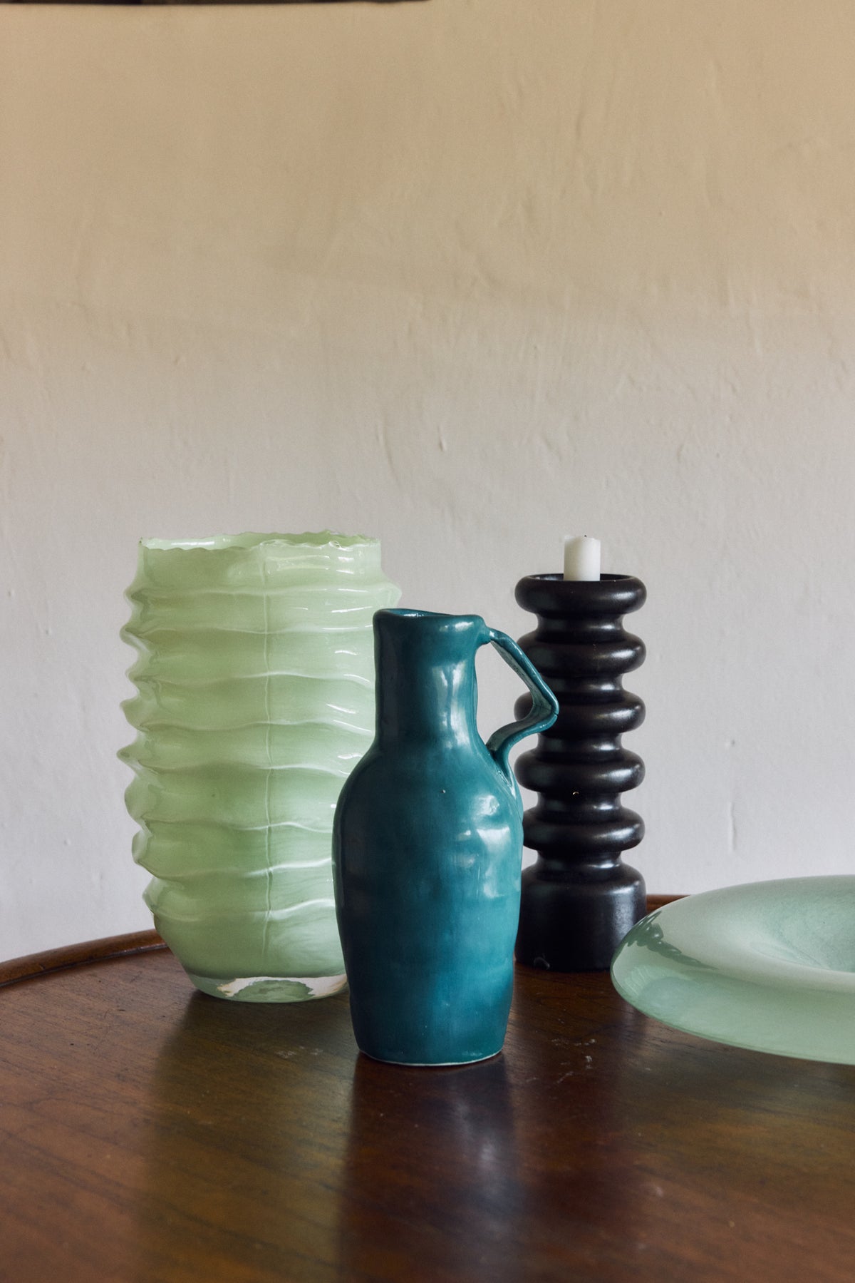 Ribble Glass Vase in Mint by HKLIVING styled on a dark wood table alongside a teal ceramic jug and black ribbed candle holder