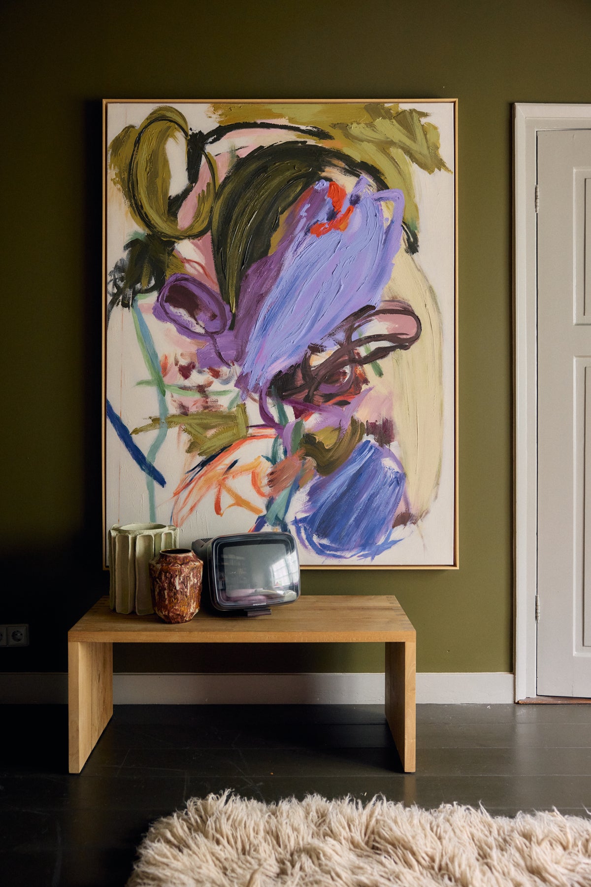 Abstraction framed artwork by HKLIVING styled above a wooden bench with ceramic vases and a vintage television, against an olive green wall