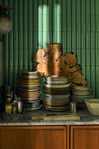Stacks of HKLIVING Chef Ceramics plates on a kitchen worktop against green tiles