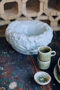 Cloud Bowl in Sky Blue styled on a glass coffee table in a floral-upholstered living room, alongside books and a ceramic vase
