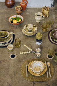 Lemon salad servers resting on a concrete tabletop styled with ceramics, amber glassware and fresh lemons
