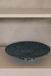 70s Ceramics Footed Fruit Bowl in Noise by HKLIVING styled on a dark stone counter, holding limes and green mangoes
