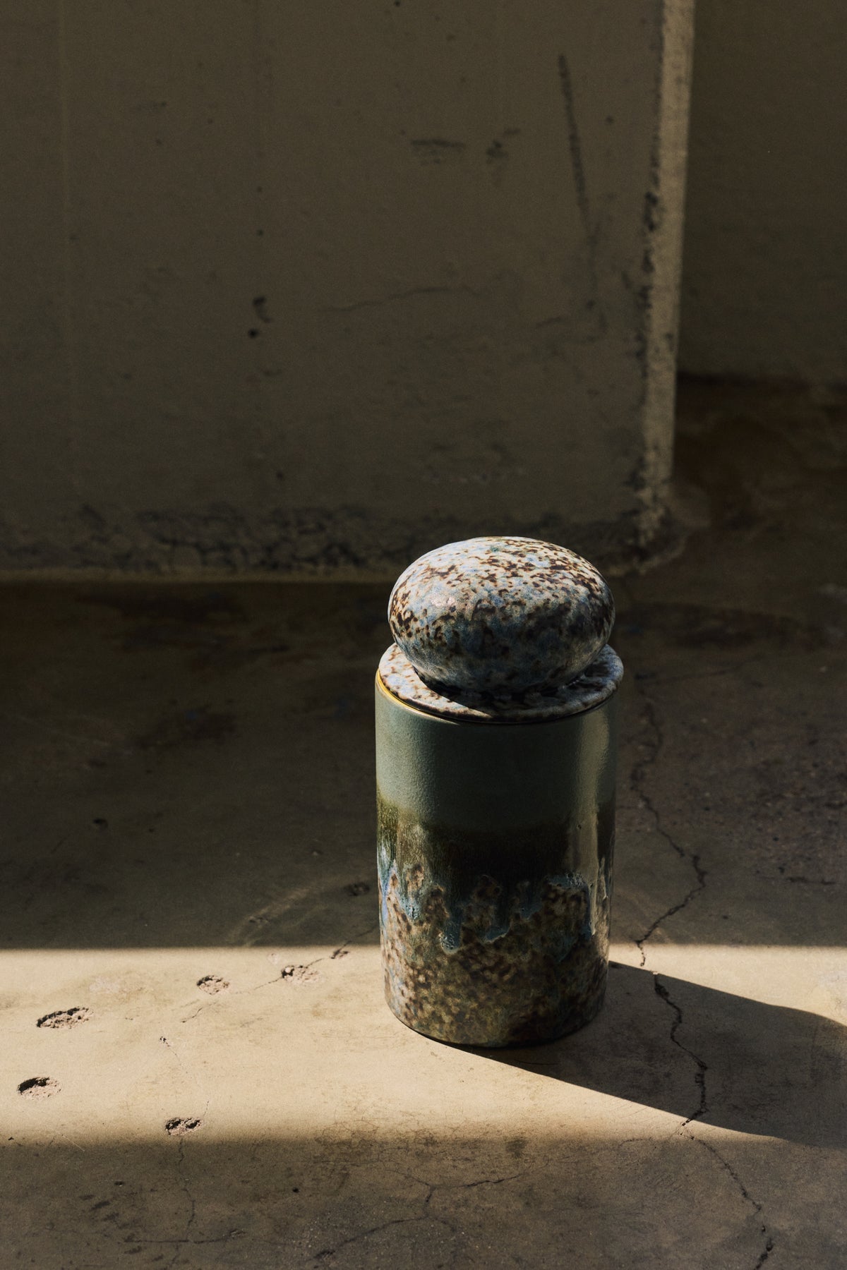 70s Ceramics Storage Jar in Agave by HKLIVING styled on a sunlit concrete step against a weathered wall