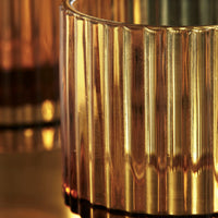 Close-up of the fluted ribbed amber glass on the House Doctor Rills tumbler, catching warm light for a cosy table feel