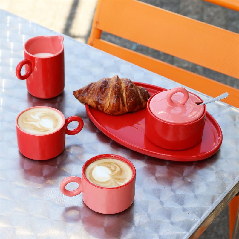 red stoneware chiquito milk jug with matching mugs on a breakfast table for colourful morning rituals