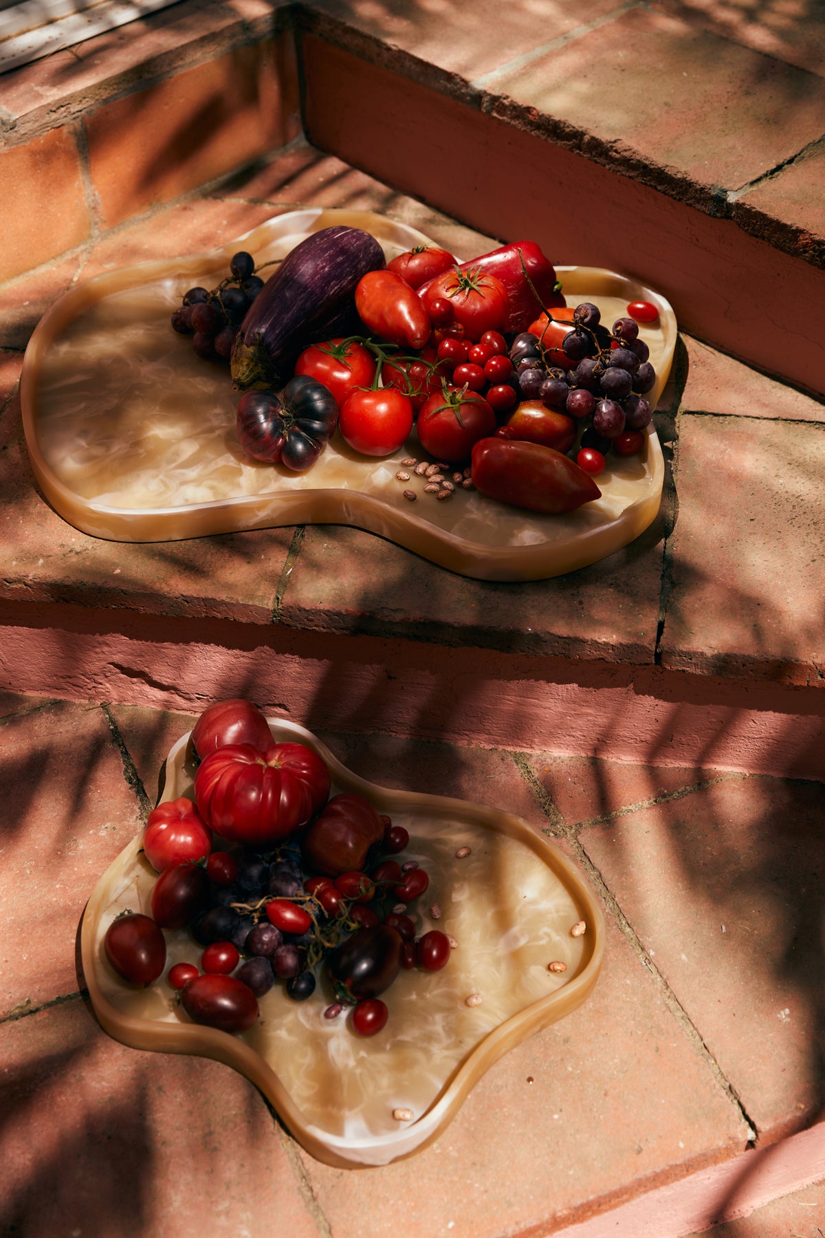 Two HKLIVING Patio marbled resin trays piled with tomatoes, cherries and berries on a sunlit terracotta floor