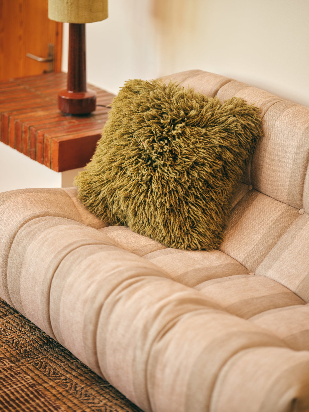 Olive green fluffy wool scatter cushion styled on sofa, cosy textured cushion by HKLIVING
