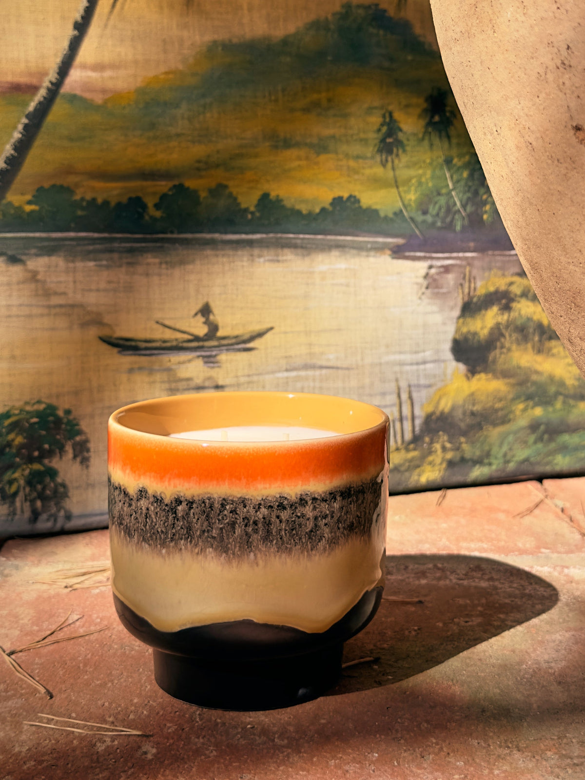 HKLIVING Tulum scented candle on a wooden table in front of a painted lake landscape