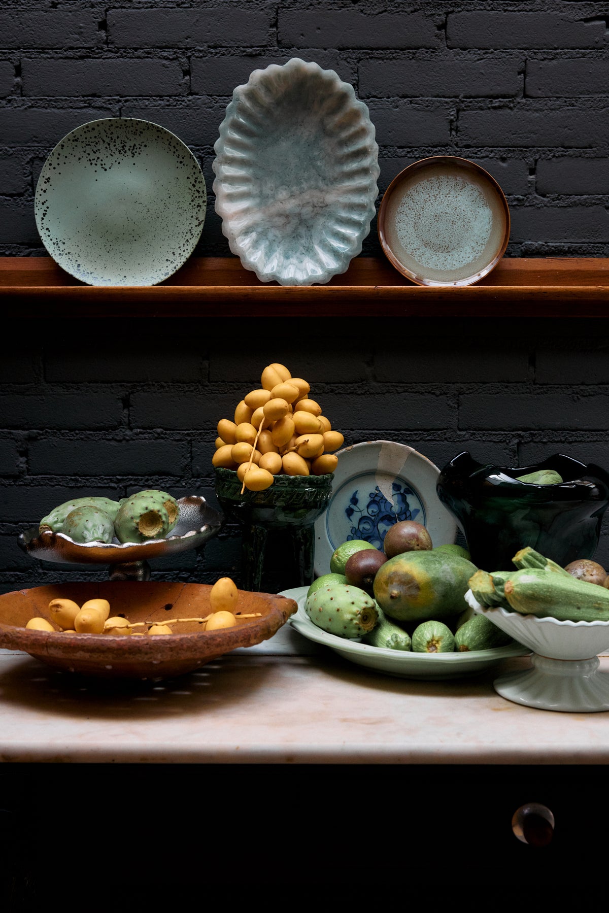 HKLIVING plates on a dark wooden shelf above a marble-topped sideboard laden with fruit