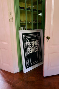Between Space framed poster by HKLIVING propped inside a glass-fronted green cabinet doorway