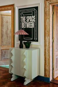 Between Space framed poster by HKLIVING hung above a mint console cabinet with a table lamp