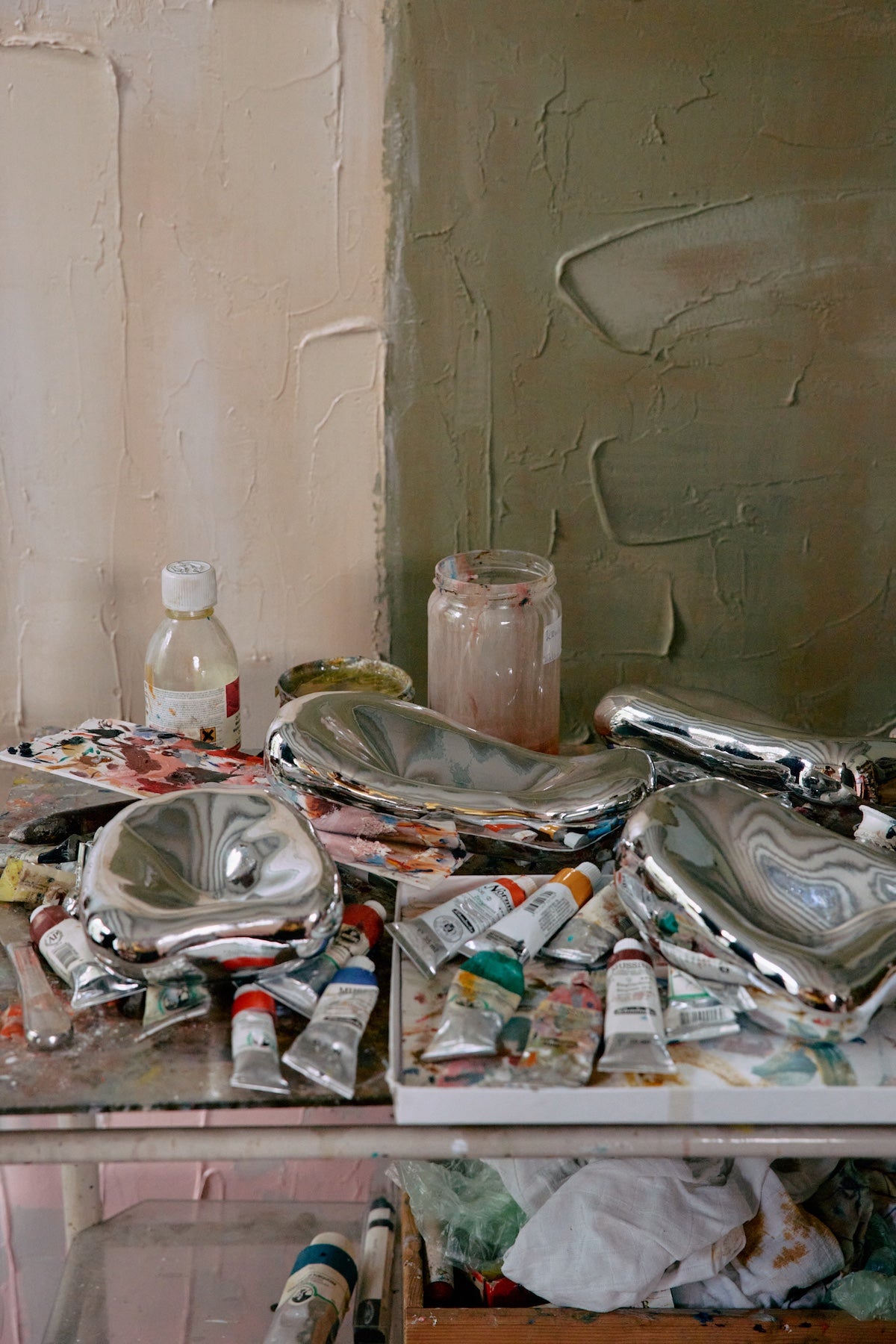 HKLIVING chrome glass wall sculptures displayed on an artist's studio table among paint tubes and palettes