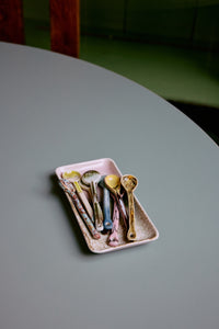 The HKLIVING Muse small tray in pink and olive stoneware, holding a set of HKLIVING Sketch spoons on a round grey table
